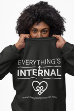 Load image into Gallery viewer, Person wearing a black unisex sweatshirt featuring the “Everything’s Internal” logo and website, promoting mindful and conscious apparel.