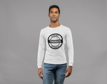 Load image into Gallery viewer, Man wearing a white "Every Internal Things" long sleeve t-shirt with bold black circular logo, paired with blue jeans, standing against a plain gray background.
