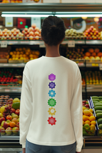 Load image into Gallery viewer, Woman wearing an ivory long-sleeve shirt with a vertical row of colorful chakra symbols printed on the back, standing in a grocery store produce section.
